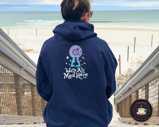 We're All Mad Here is a whimsical keyhole design on a comfy zip-up hoodiethe perfect gift for Alice in Wonderland Fans and Tea Lovers.