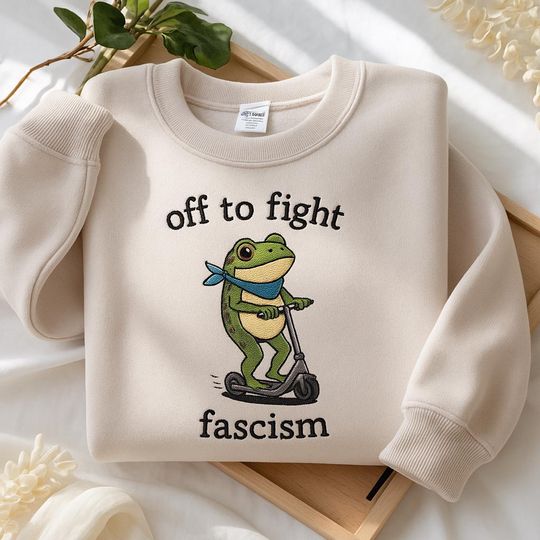 Discover Embroidered Off to Fight Fascism Portland Frog sweatshirt, Protest Frog on Scooter pullover, subtle anti trump shirt